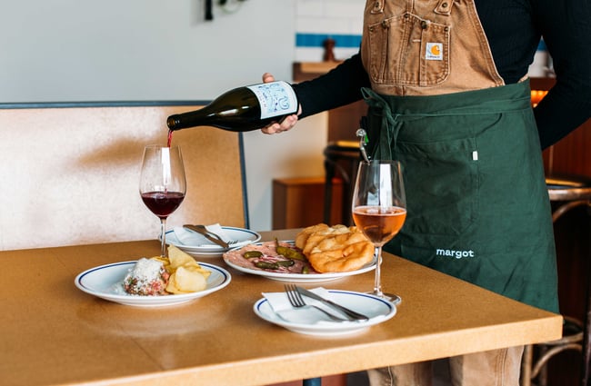A staff member pouring wine into a glass.