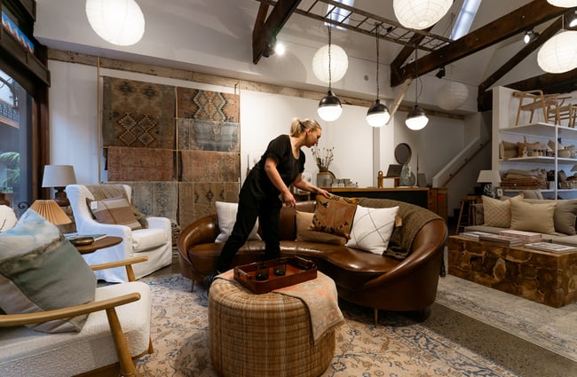 A staff member organising a cushion on a couch.