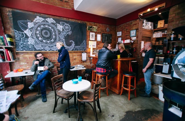 People sitting up at high chairs and tables inside Mazagran.