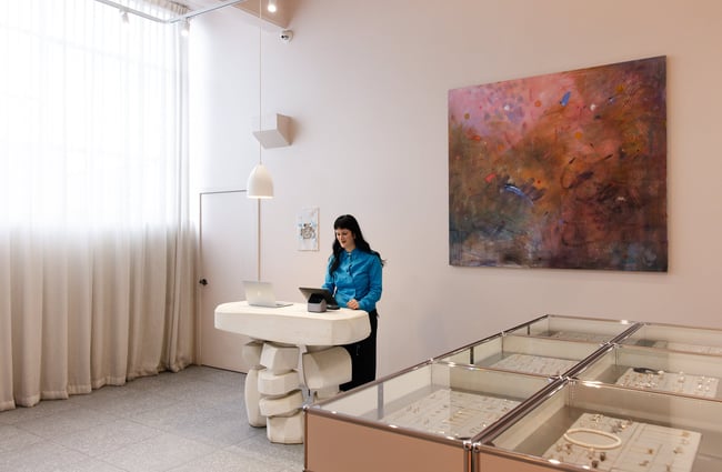 A woman in a blue shirt working inside Meadowlark Jewellery Auckland.