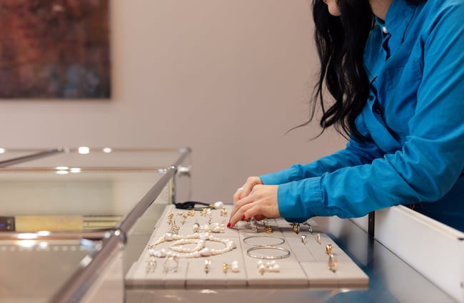 A close up of hands touching jewellery.