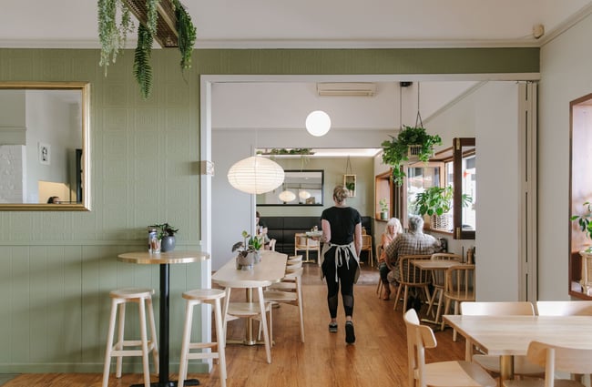 A staff member delivering a plate of food to a table at Mint Folk and Co in Twizel.