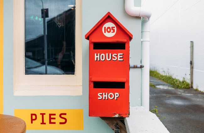 Red retro wooden letterbox with "pie" written on the wall next to it
