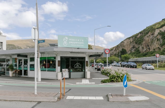 The exterior of the Miss Peppercorn restaurant with a sage green sign.
