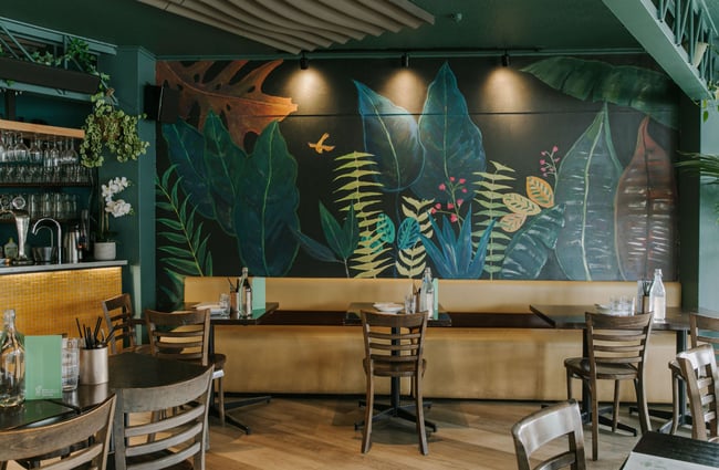 The tables along the wall with a leaf covered wall paper.