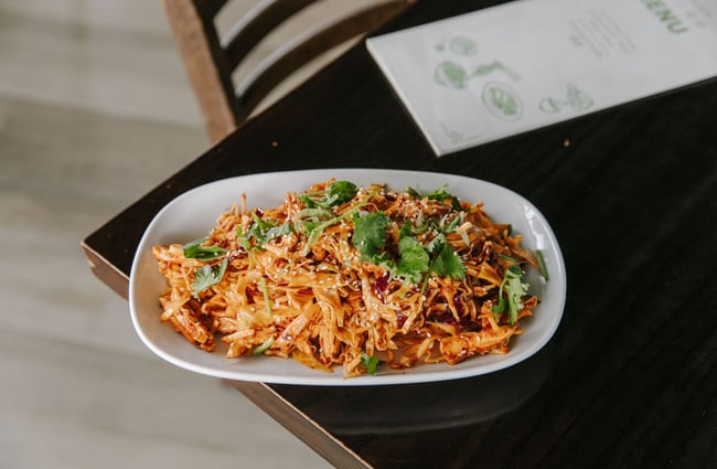 A big shared plate of a tomato pasta with basil and cheese on top.