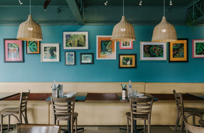 Tables along the wall at Miss Peppercorns with cane lampshades above the tables.