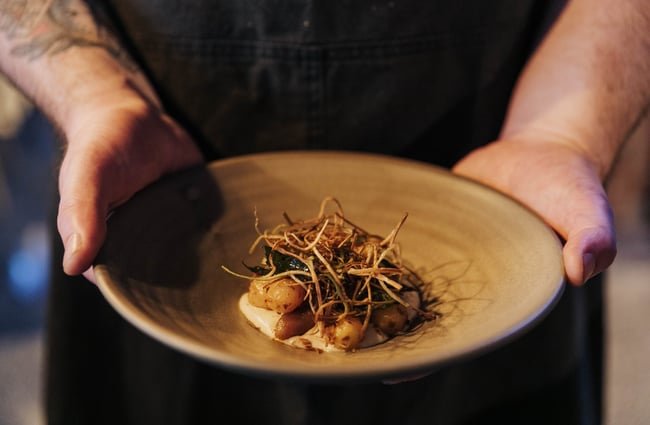A chef holding a plate of food.
