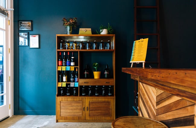 Wooden cabinet adorned with bottles of red wine and glass riggers at Monkfish, Wellington.