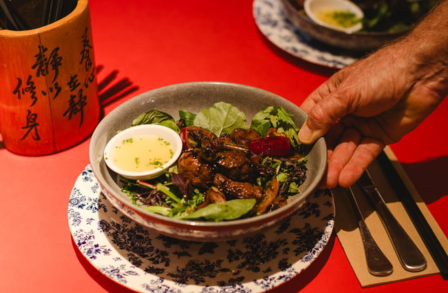 Food dish being placed on a table at Monsoon Poon.