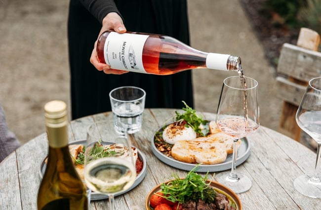 Wine being poured into a glass and dishes on the table at Monte Christo Winery.