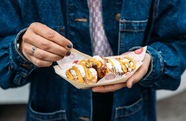 Hands holding a waffle on a tray.