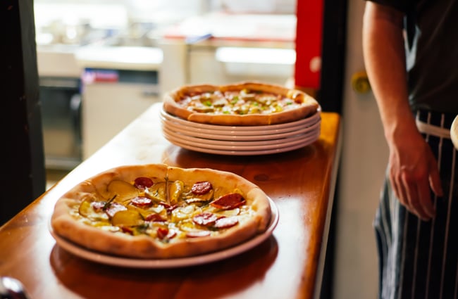 Pizza on plates by kitchen.