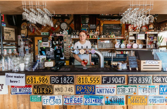 Woman pouring a pint behind the bar at Moon Under Water, Christchurch.