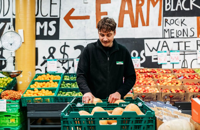 Worker picking up butternut squash at Moore Wilson's in Wellington