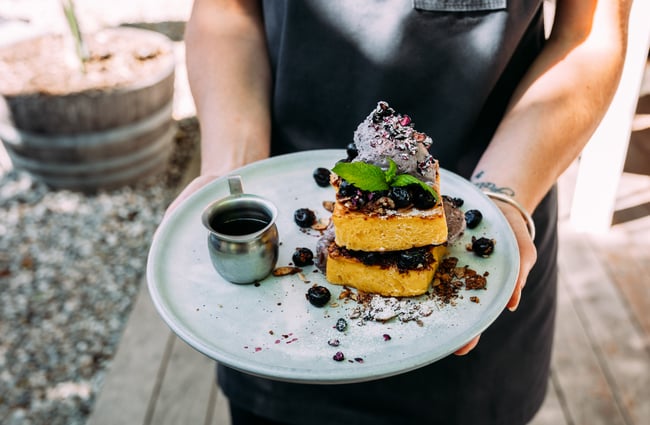 Hands holding a plate of dessert.