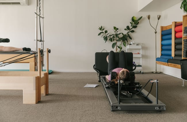 A close up of a woman on a reformer machine.