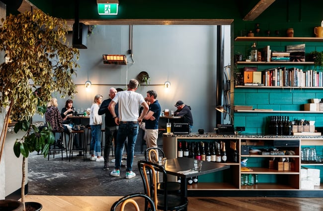 Looking through the Mr. Pickles restaurant to a group of people standing in the laneway.