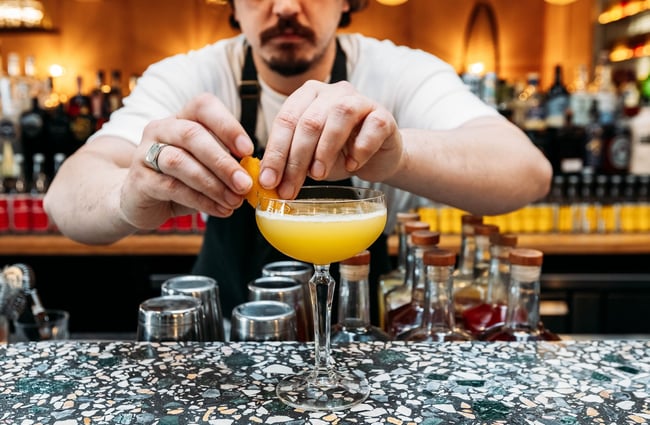 Close up of a bartender garnishing a cocktail.