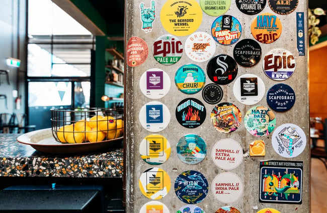 A bowl of lemons sits on the bar beside a concrete pillar that's plastered with the badges of previous tap beers.