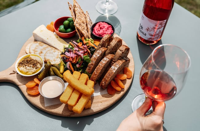 A cheese platter and a glass of rose wine.