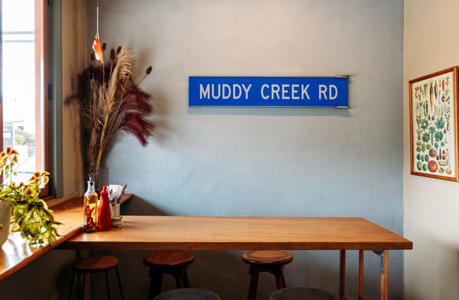 A 'muddy creek rd' sign on a wall.