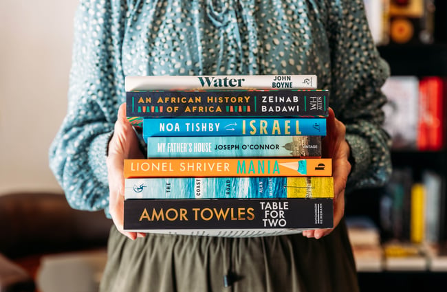 Hands holding a set of books.