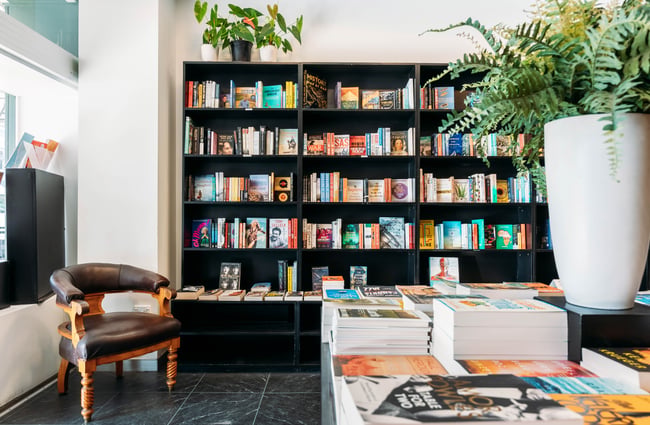 Books on display on a black shelf in a brightly lit bookshop.