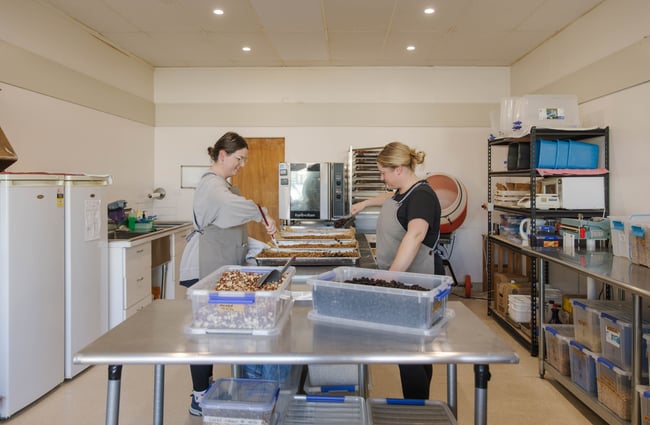 Two shop assistants in the kitchen making muesli at Mumma Bear.