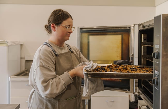 Shop assistant putting a tray into the oven at Mumma Bear.