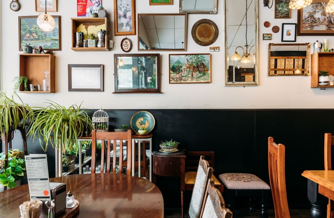 Tables and chairs in cafe with a wall lined with art work.