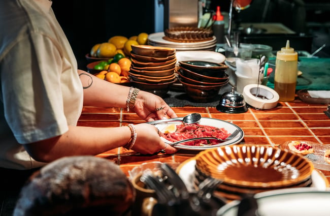 A dish is presented at the kitchen pass by a chef at Muttonbird.
