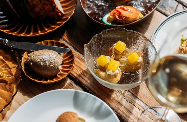 Four thick slices of fresh bread on a retro glass leaf plate with a ramekin of fennel seed butter in the background.