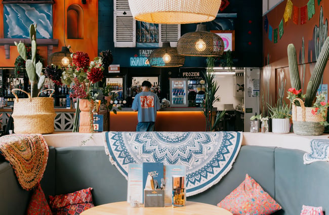 Man standing at bar surrounded by colourful decor at Muy Muy in Christchurch