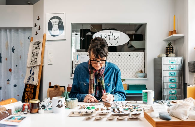 A woman painting at a desk.