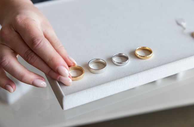 Men's wedding bands are placed on a display tray by the shop assistant at Naveya & Sloane Jewellery.