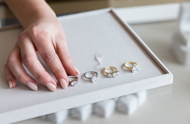 Shop assistant places rings on a display tray in Naveya & Sloane Jewellery.