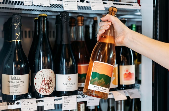 Customer picking a bottle of sparkling wine out of the fridge at Neat at Made.