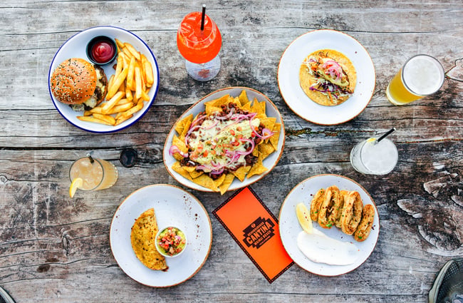 Flatlay of food dishes on a table, including nachos, burger and other items at Neighbourhood Cantina.