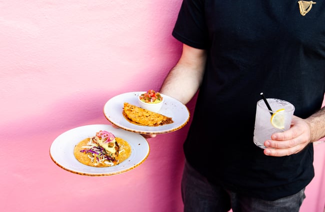 Waiter serving plates of tacos and a cocktail at Neighbourhood Cantina.