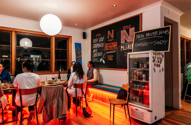 Customers sitting inside an orange lit restaurant.