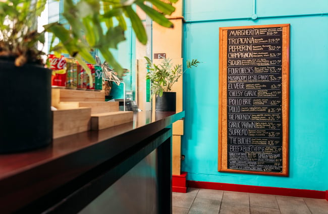 A large chalkboard menu on a wall inside Neptunes Pizzeria Gisborne.