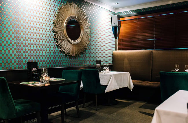 Seating area inside the restaurant with a big round mirror.