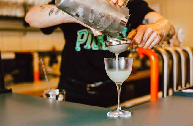 Man pouring a cocktail into a glass at Next Door, Wellington.