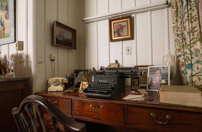 A type writer on an old wooden desk.