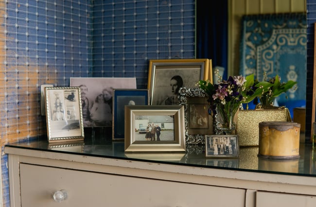 An old dresser with framed pictures on top.