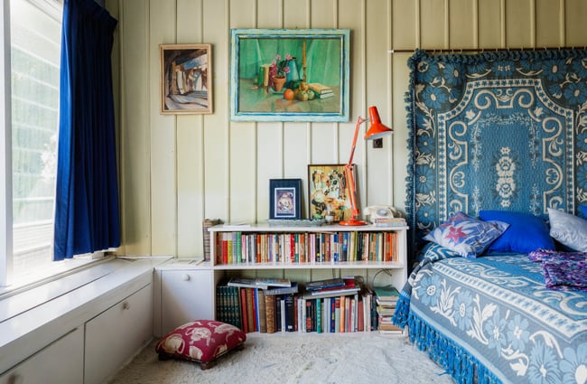A colourful bookshelf by an old bed in the Ngaio Marsh House.