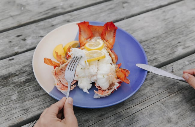 Someone eating crayfish with knife and fork.