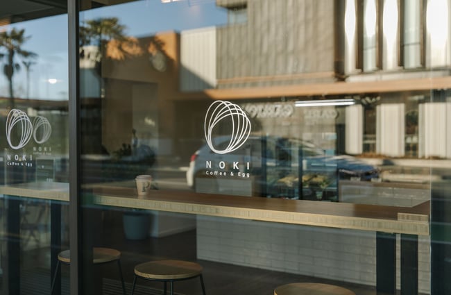Window decal of NOKI with coffee and egg written underneath