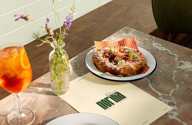 A pizza and a cocktail on a table.